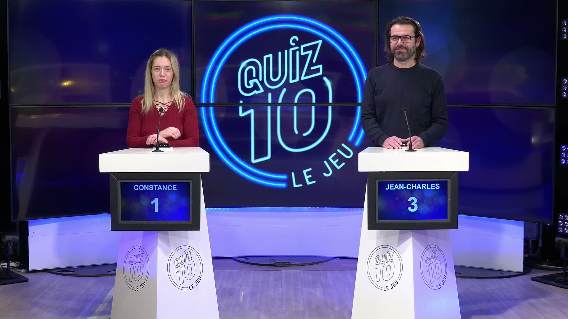 Deux candidats debout face à leurs pupitres avec le logo Quiz 10 en arrière-plan